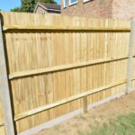New wooden fencing with concrete posts installed in a landscaped garden