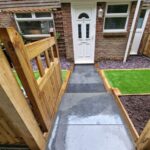 A front garden that has been landscaped with new artificial grass, wooden fences and a gate.