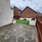 A garden with a grey patio that has had new artificial grass installed.
