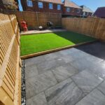A garden with a grey patio that has had new artificial grass installed.